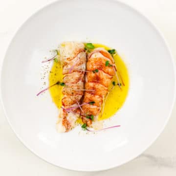 sous vide lobster tail on butter sauce in a white bowl