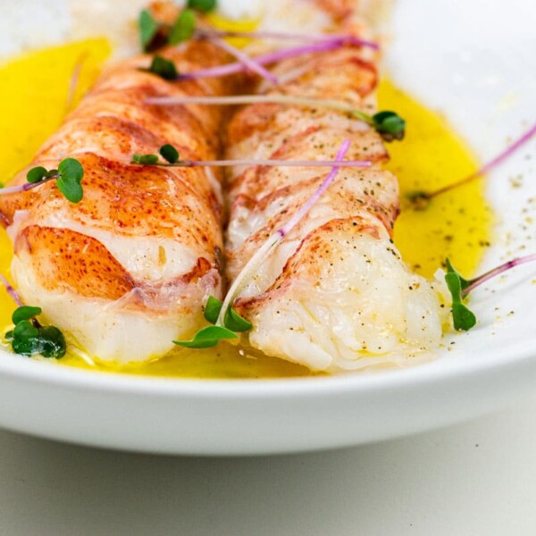 sous vide lobster tail on butter sauce in a white bowl