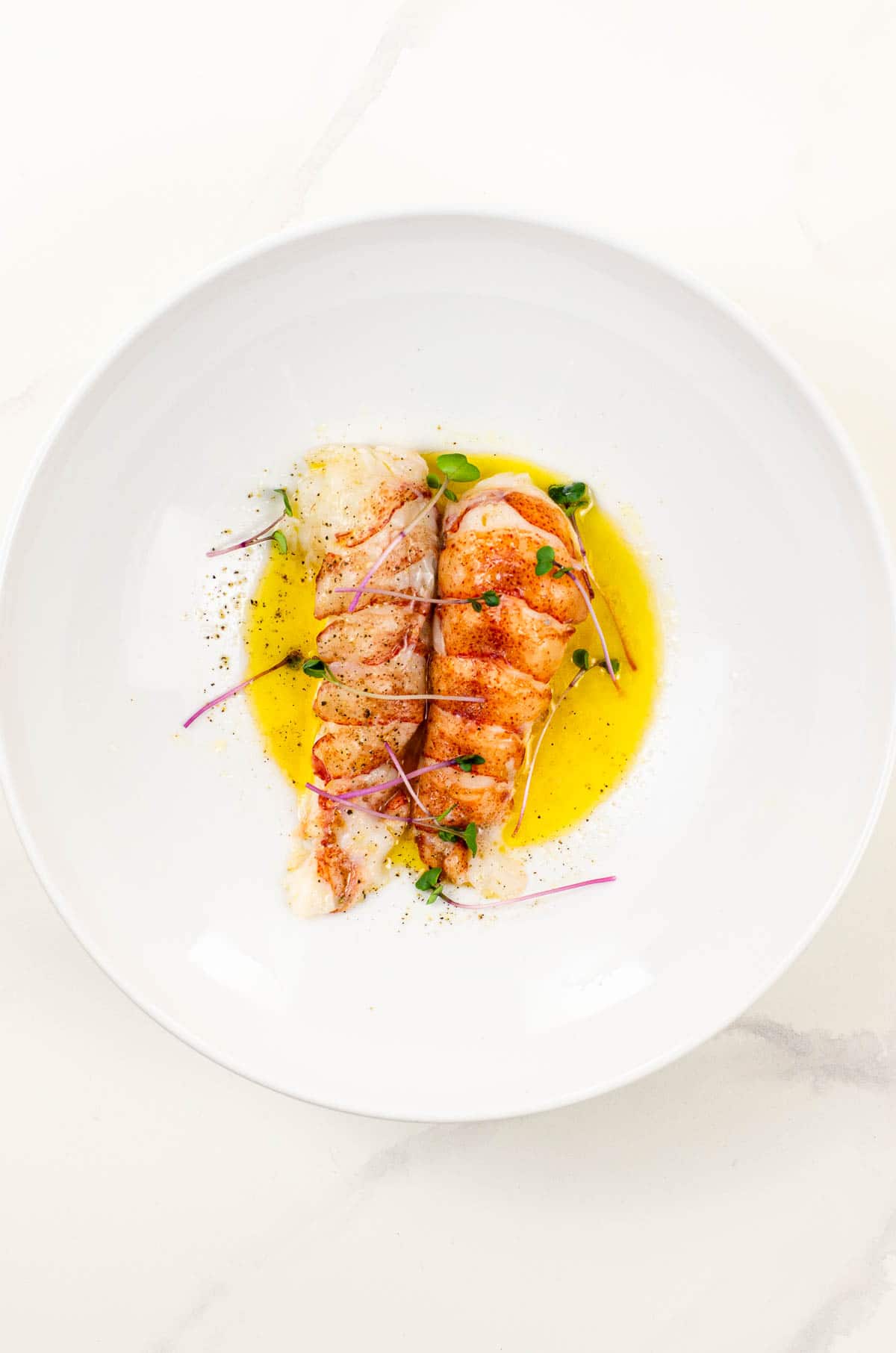 sous vide lobster tail on butter sauce in a white bowl