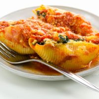 three stuffed pasta shells on a plate with a fork