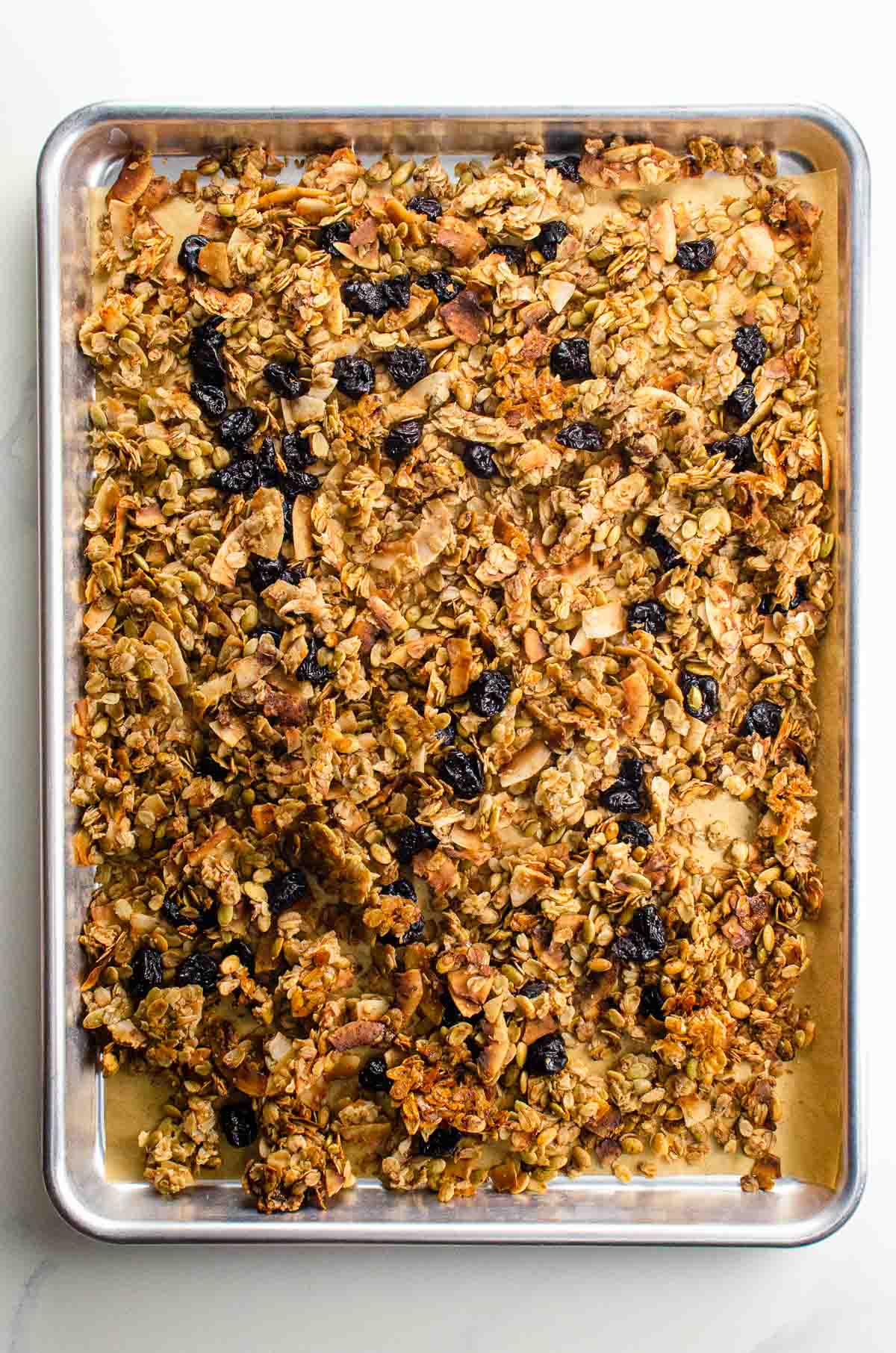 cinnamon granola with almonds, coconut, and dried cherries on a sheet pan