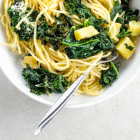 creamy kale pasta with potatoes, lemon, and capers in a white bowl