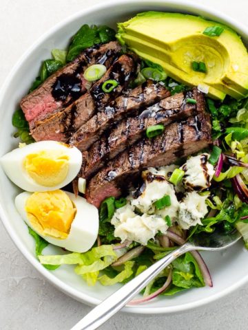 flank steak salad with blue cheese and avocado in a white bowl
