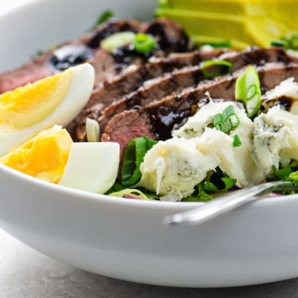 flank steak salad with blue cheese and avocado in a white bowl