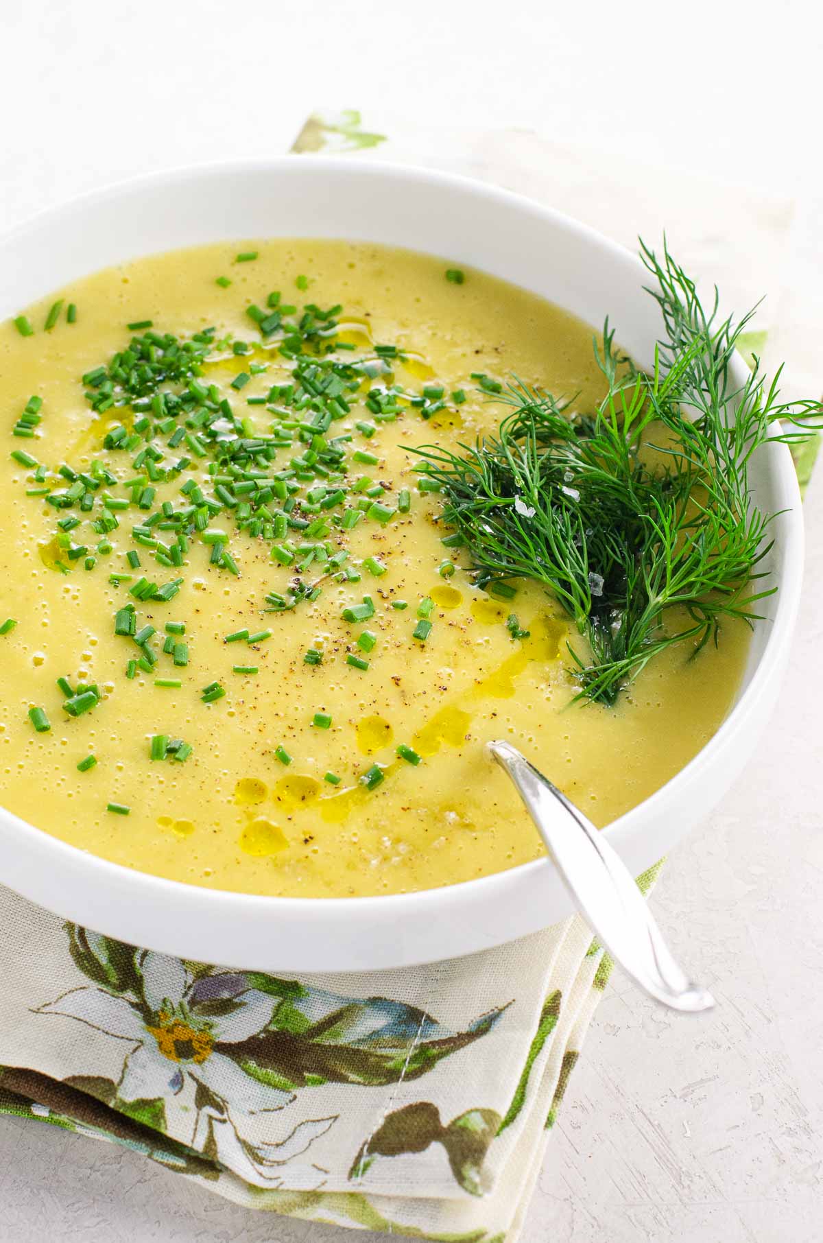 potage parmentier (potato leek soup) in a white bowl garnished with dill and chopped chives