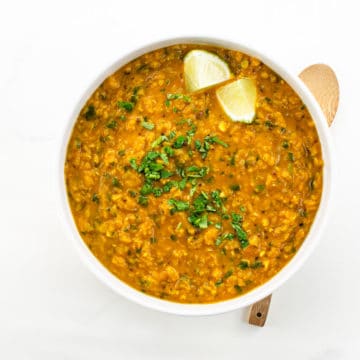 Red Lentil Dahl with Coconut Milk in a bowl with lime and cilantro garnish