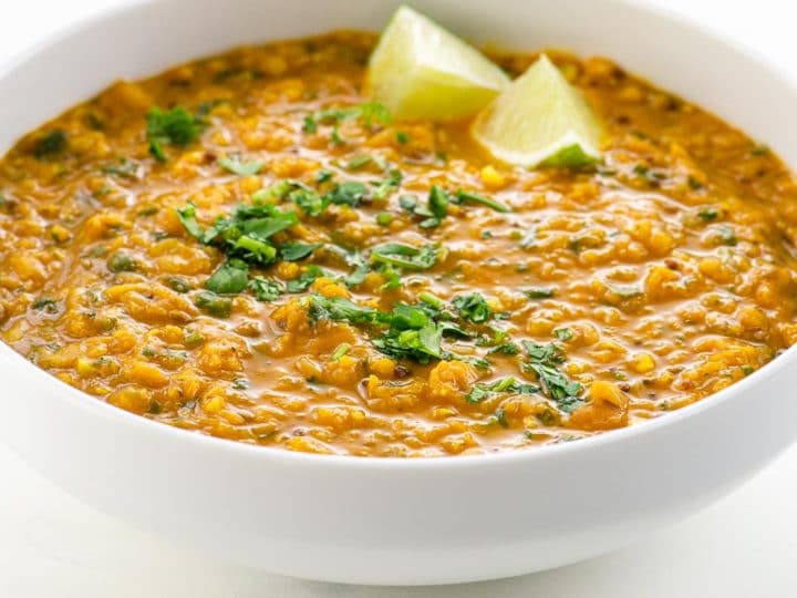 Red Lentil Dahl with Coconut Milk in a bowl with lime and cilantro garnish