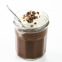 chocolate pudding with whipped cream and chocolate shavings in a jam jar with a spoon