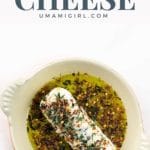 marinated goat cheese appetizer with olive oil and spices in an orange serving dish