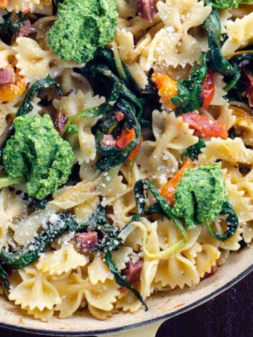 farfalle pasta with ramps, ramp pesto, cherry tomatoes, and soppressata in a pan