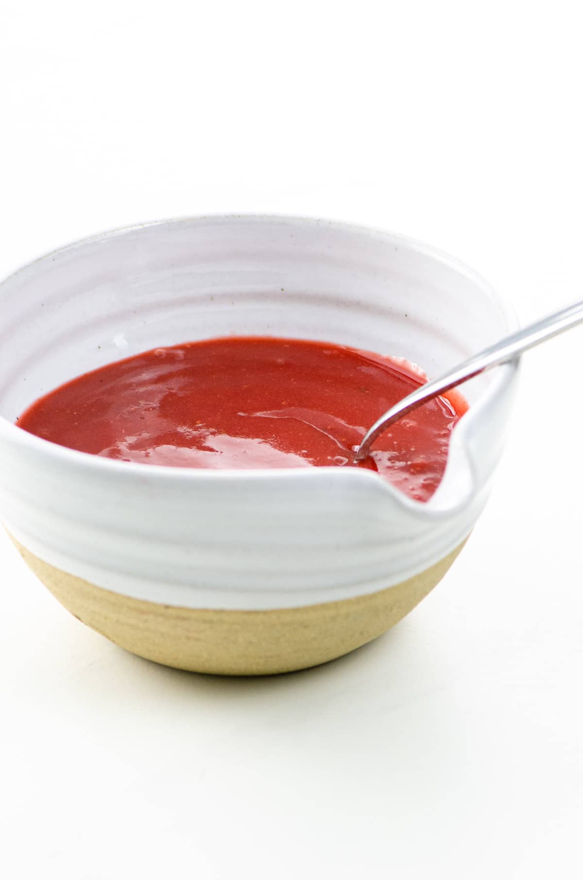 strawberry sauce for cheesecake in a bowl with a spoon