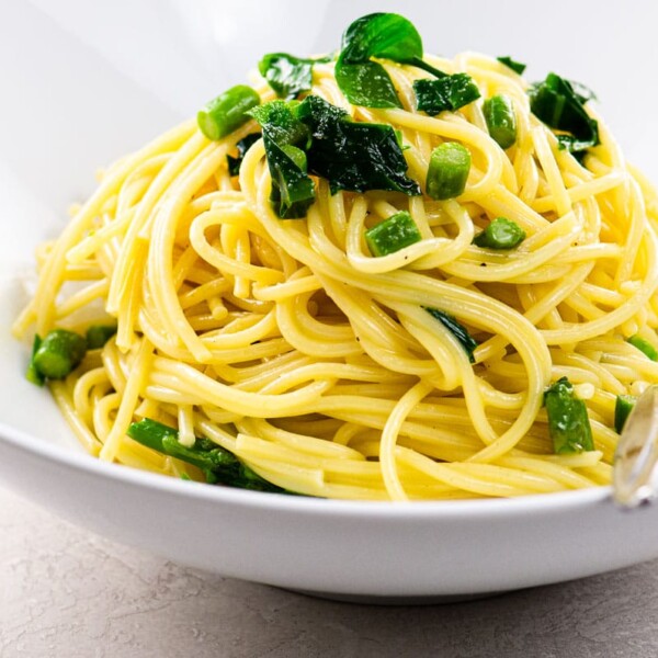 vegetarian spaghetti carbonara with asparagus and ramps in a white bowl