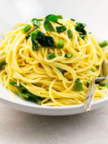 vegetarian carbonara with asparagus and ramps in a white bowl