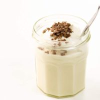 classic vanilla pudding with whipped cream and chocolate shavings in a jam jar with a spoon