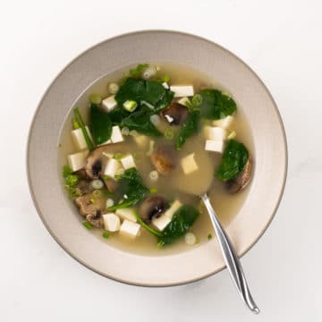 miso soup with mushrooms and spinach in a bowl with a spoon