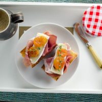prosicutto brie and apricot toasts on a tray with coffee for mother's day breakfast in bed