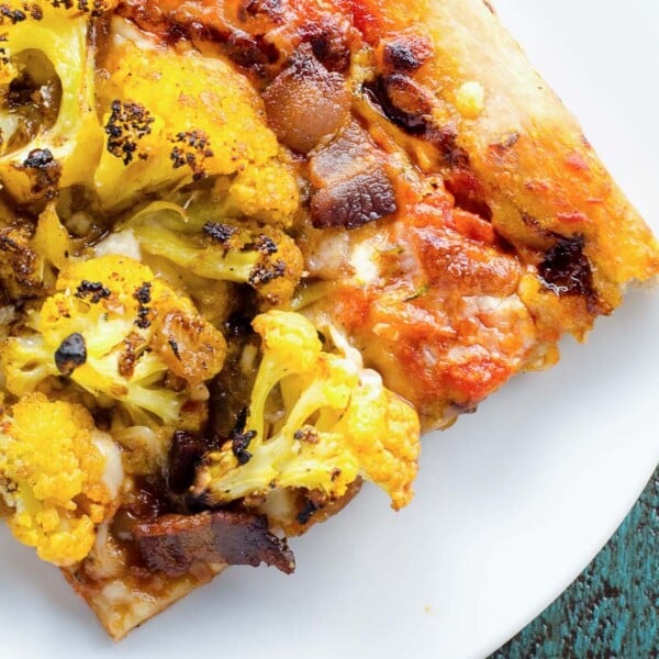 a slice of pizza amatriciana with cauliflower on white plates