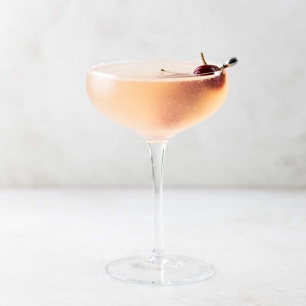 French 75 Sour Cherry Cocktail in a coupe glass garnished with homemade maraschino cherries