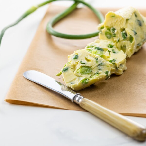 garlic scape butter on parchment with a small knife and a garlic scape