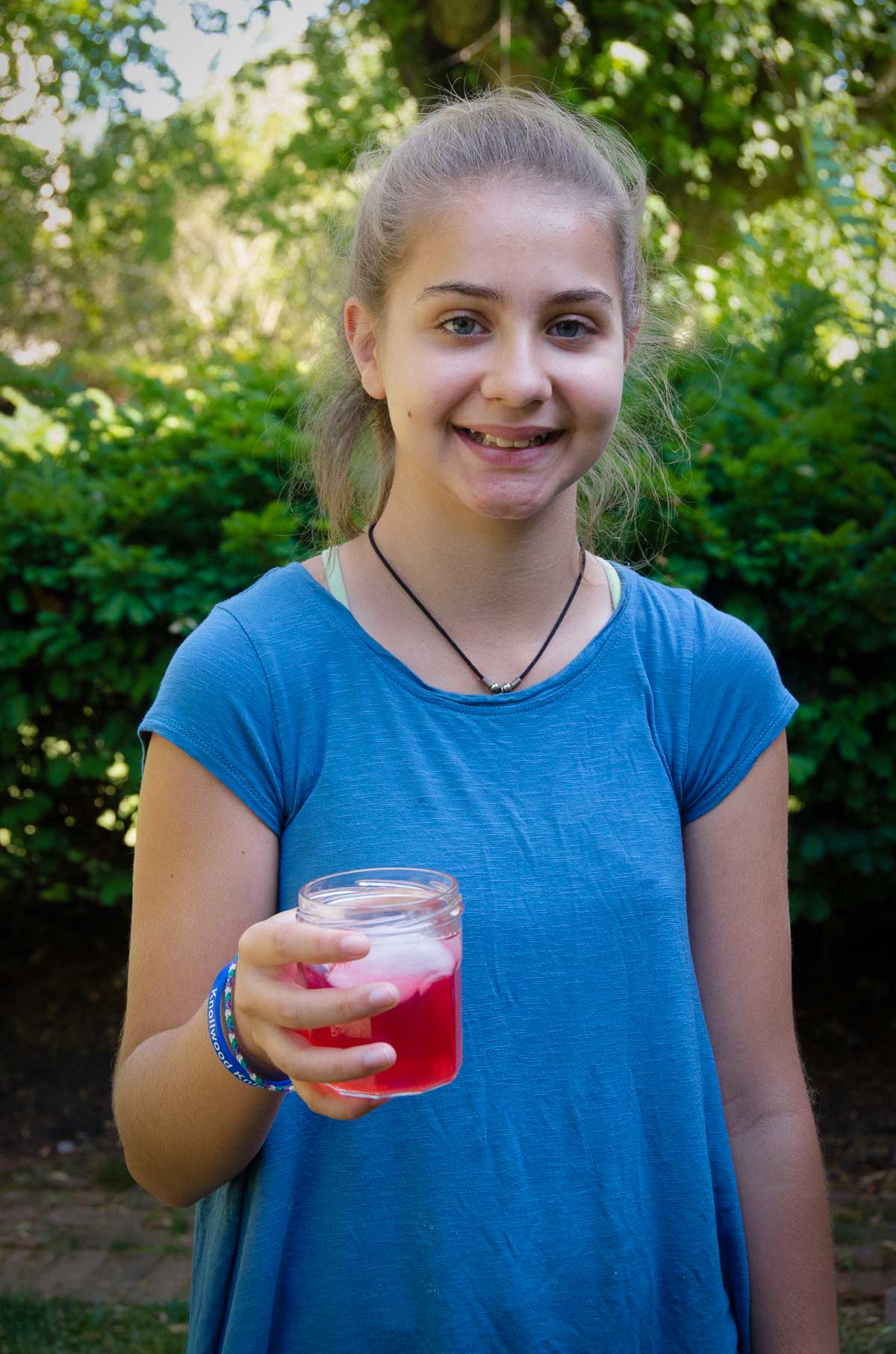 child standing outside smiling and holding a shirley temple
