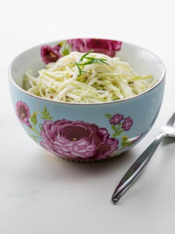 kohlrabi remoulade in a beautiful blue and pink bowl with a fork