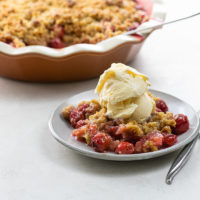 sour cherry crisp a la mode in a deep dish pie plate and on a plate