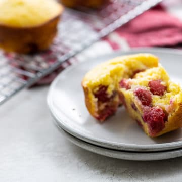 a sour cherry muffin on plates with more on a cooling rack and red and white towel