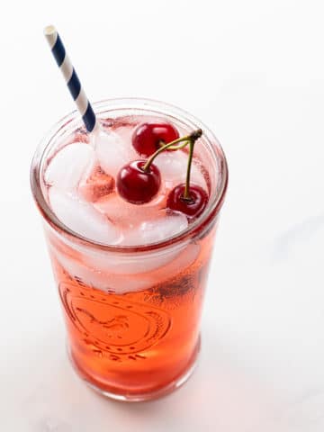 shirley temple recipe with sour cherries in a glass with a straw