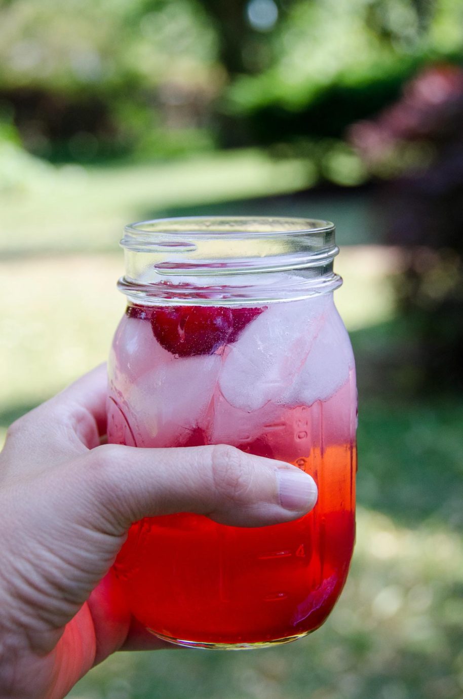 sour cherry shirley temple in someone's hand outdoors