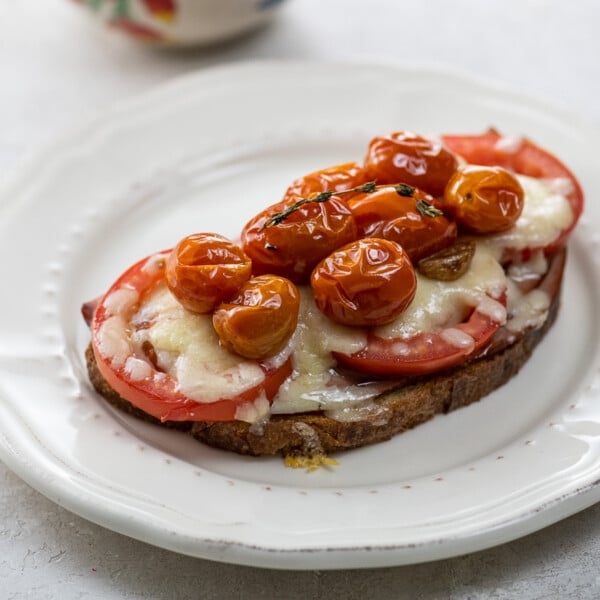 open face grilled cheese with ham, tomatoes, gruyere, and tomato confit on a plate