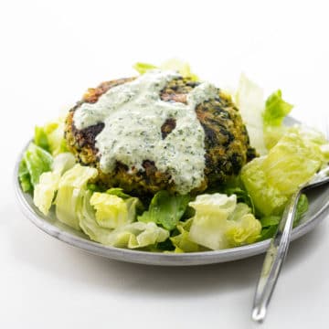 a fava bean burger on a small plate with lettuce and green goddess dressing