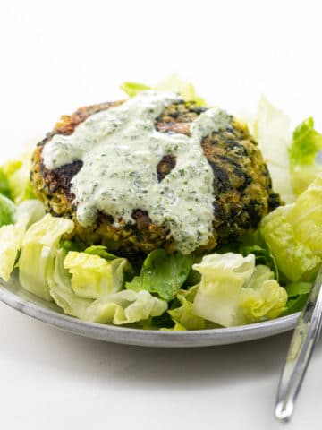 a fava bean burger on a small plate with lettuce and green goddess dressing
