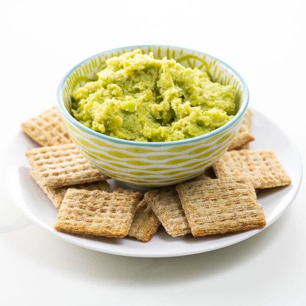 a bowl of fava bean puree with crackers on a plate