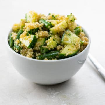 a bowl of quinoa salad with green vegetables and a fork