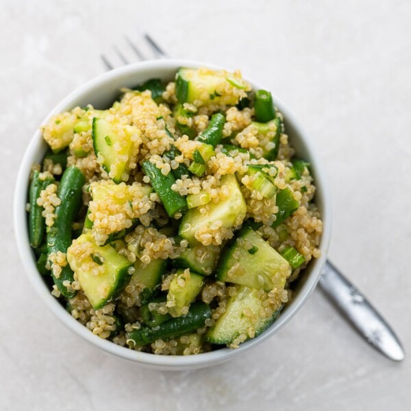 a bowl of quinoa salad with green vegetables and a fork