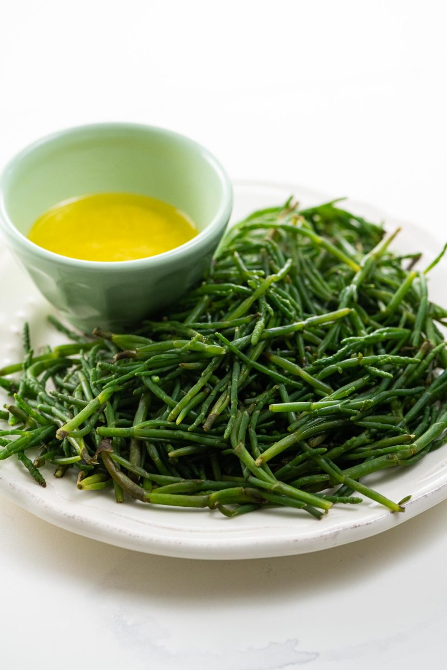 sea beans on a plate with a bowl of lemon butter for dipping