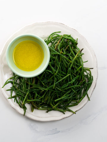 sea beans on a plate with a bowl of lemon butter for dipping