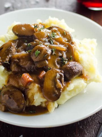 mushroom bourguignon (vegan option) on a plate with mashed potatoes and a glass of red wine