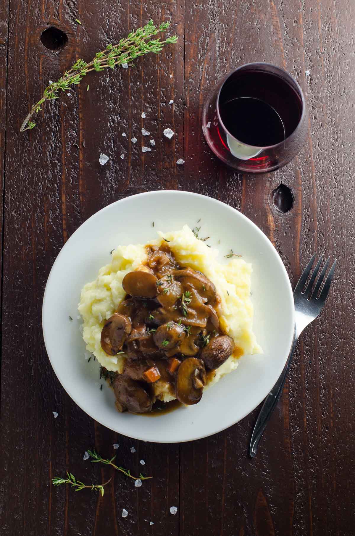 mushroom bourguignon (vegan option) on a plate with mashed potatoes and a glass of red wine