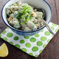 chickpea salad with Indian spices and yogurt in a bowl with a paper napkin and lemon wedge