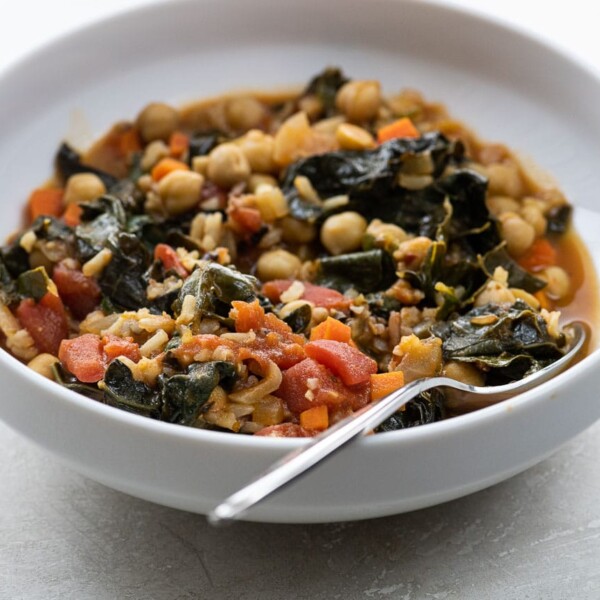 kale and chickpea stew in a white bowl with a spoon