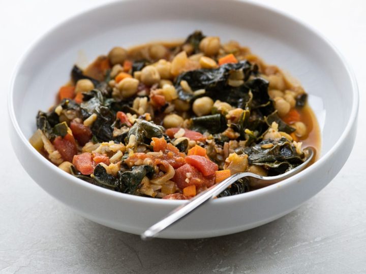 kale and chickpea stew in a white bowl with a spoon