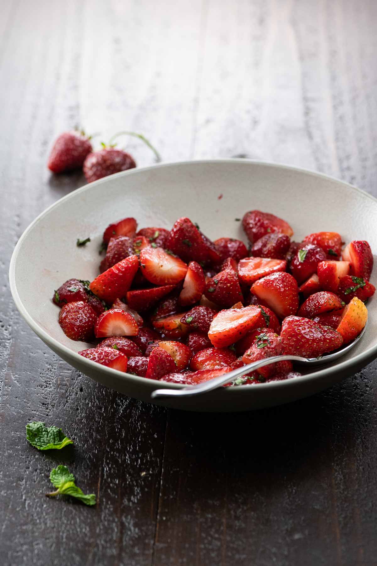 a bowl of cut strawberries with mint