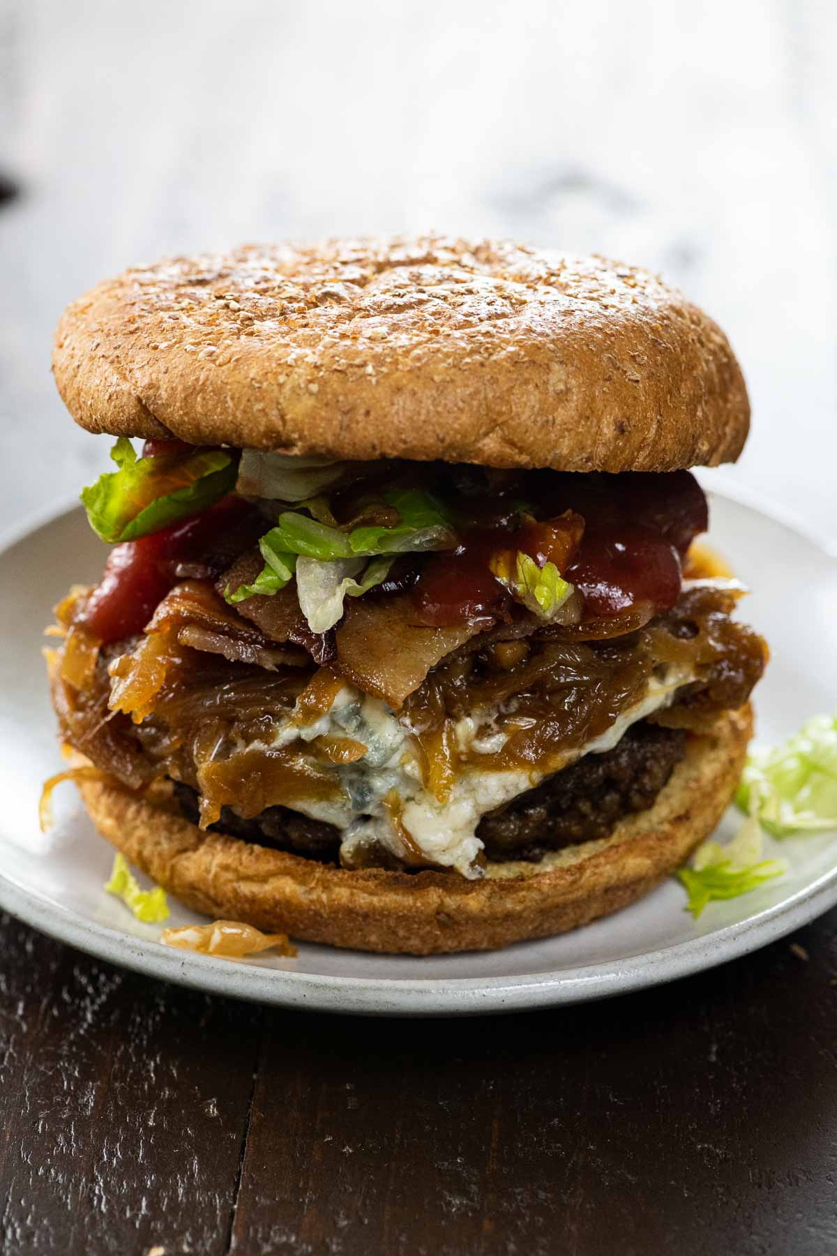 bacon weave blue cheese burger with caramelized onions, lettuce, and ketchup on a small plate