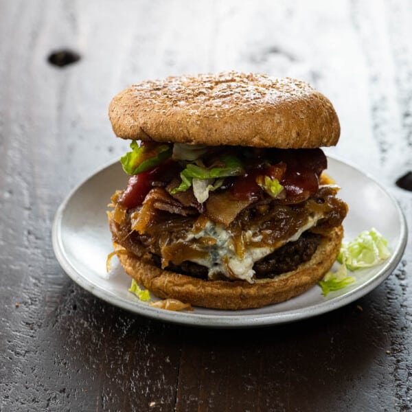 bacon weave blue cheese burger with caramelized onions, lettuce, and ketchup on a small plate