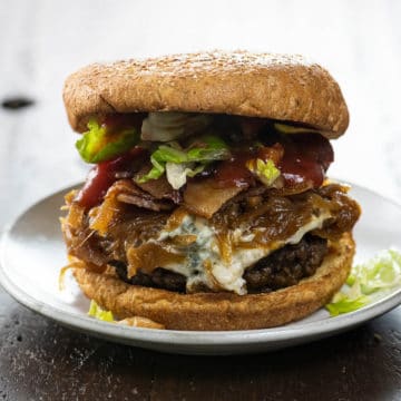 bacon weave blue cheese burger with caramelized onions, lettuce, and ketchup on a small plate