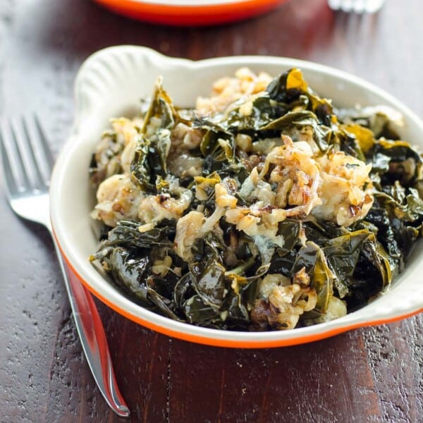 braised kale with caramelized onions, walnuts, and blue cheese in a gratin dish with a fork