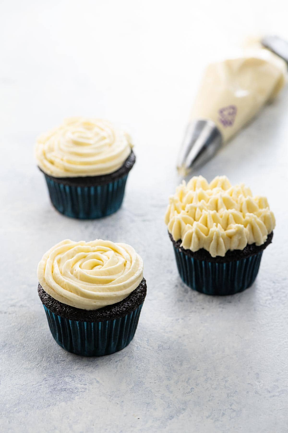 chocolate cupcakes with stable whipped cream cheese frosting for piping, and frosting in a piping bag