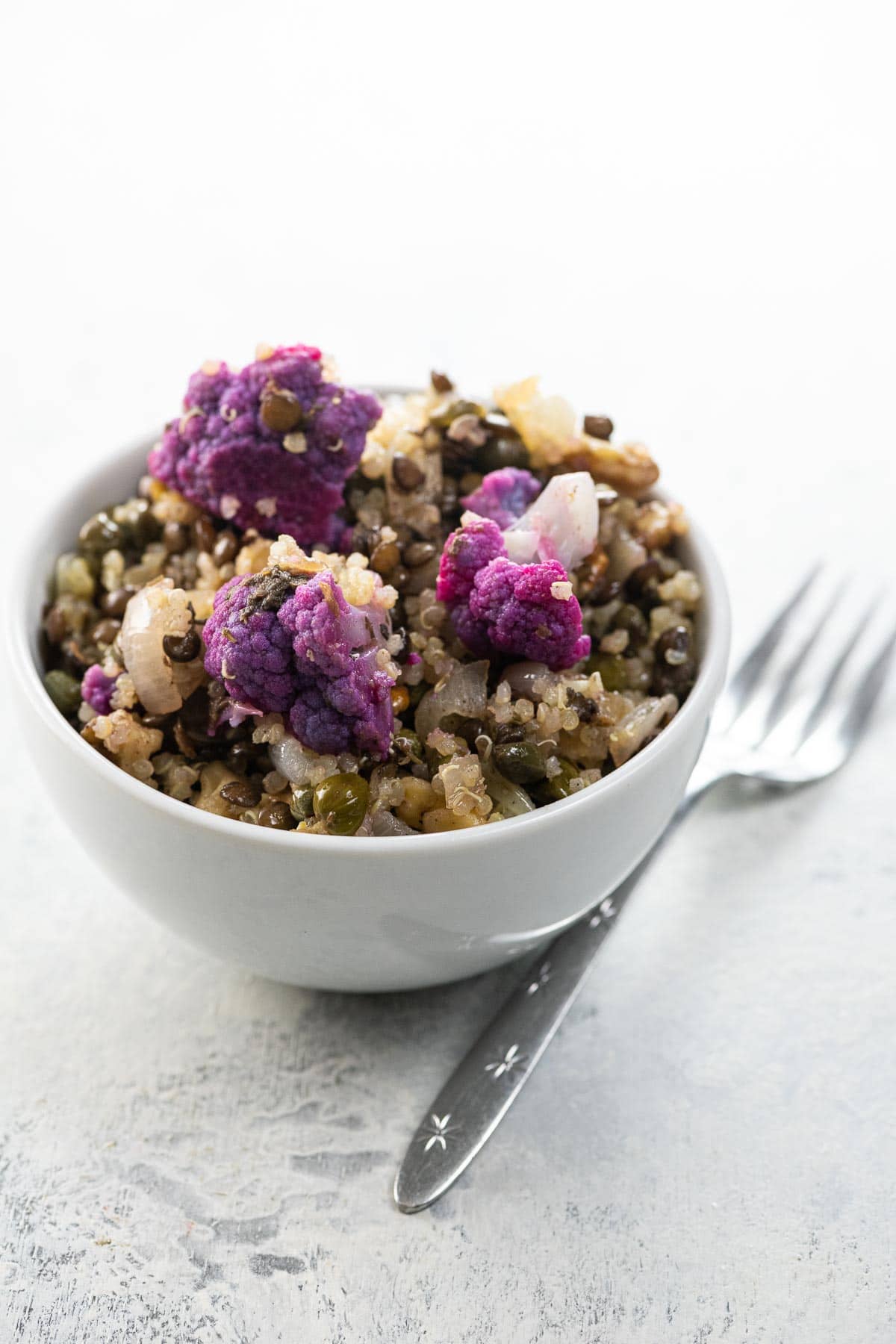 warm quinoa salad with lentils and cauliflower in a white bowl