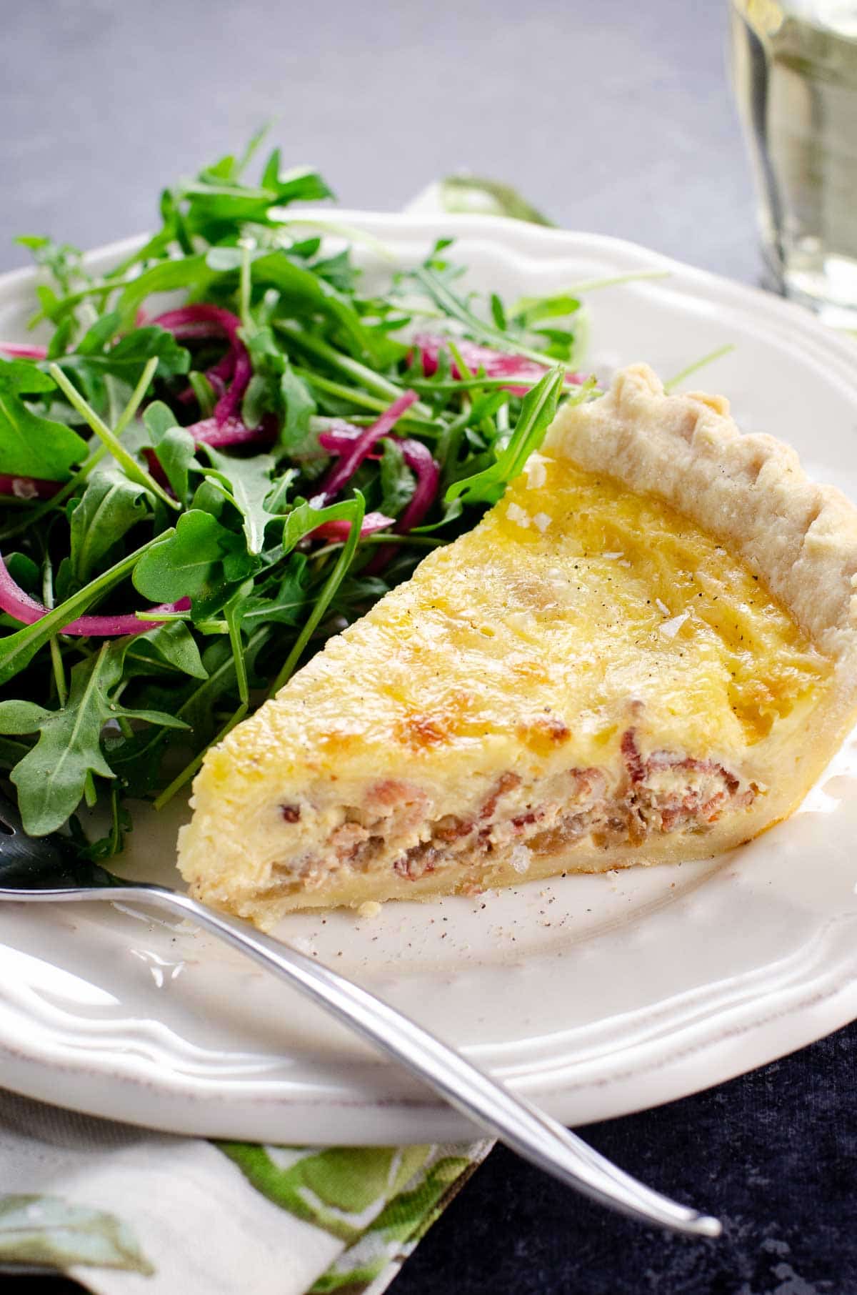 a slice of French Quiche Lorraine and salad on a plate
